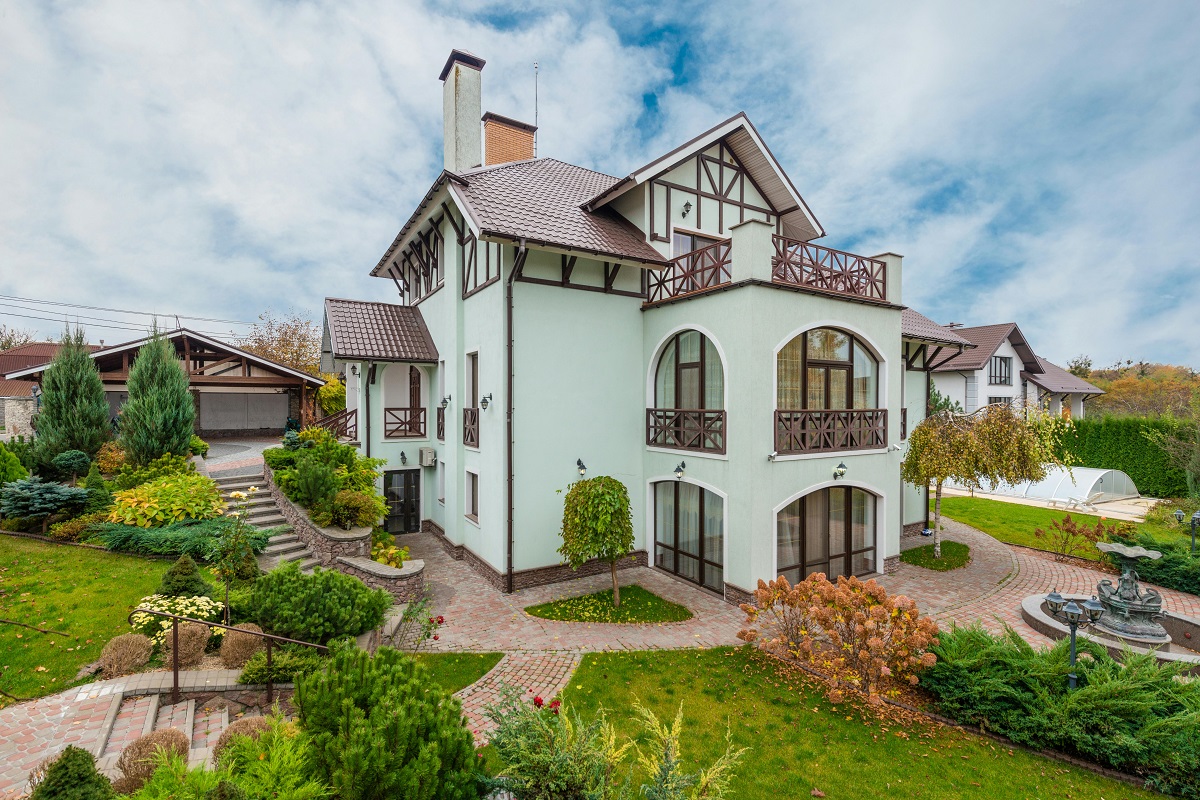 modern tudor-style home with a front yard full of plants and trees